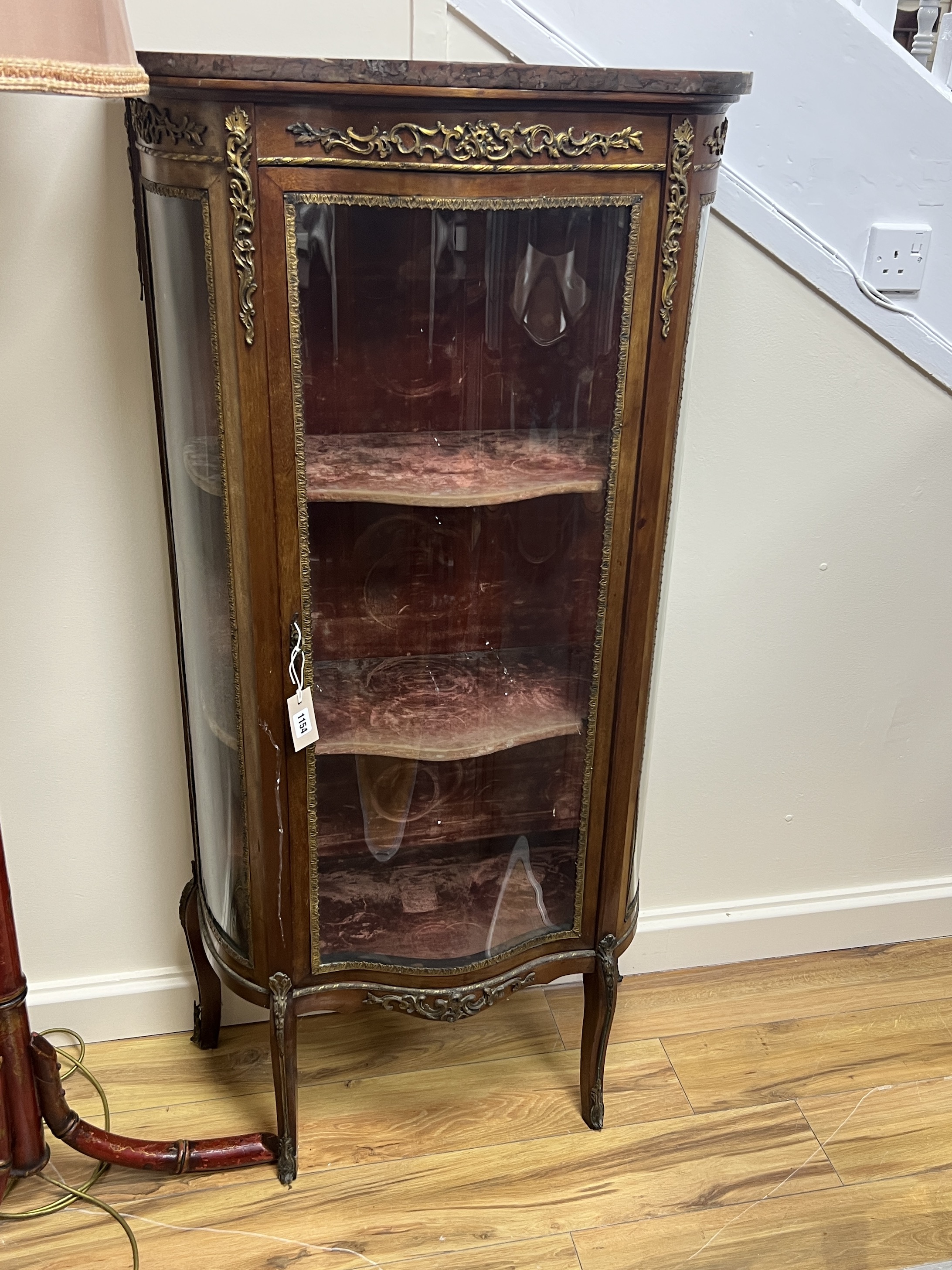 A Louis XVI style gilt metal mounted marble topped serpentine vitrine, width 70cm, depth 33cm, height 140cm